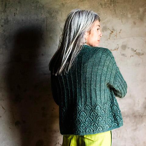 Ryggen på Thelma fremhæver de elegante, lodrette linjer, der smukt munder ud i et dekorativt blomsterpanel. Online strikkekursus med grundig vejledning og video.